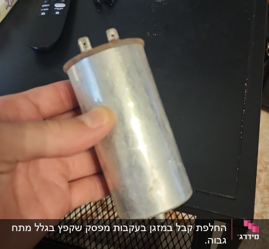 יד מחזיקה רכיב מתכתי על שולחן שחור